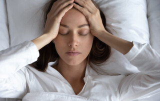 woman suffering from migraine headache, lying in bed